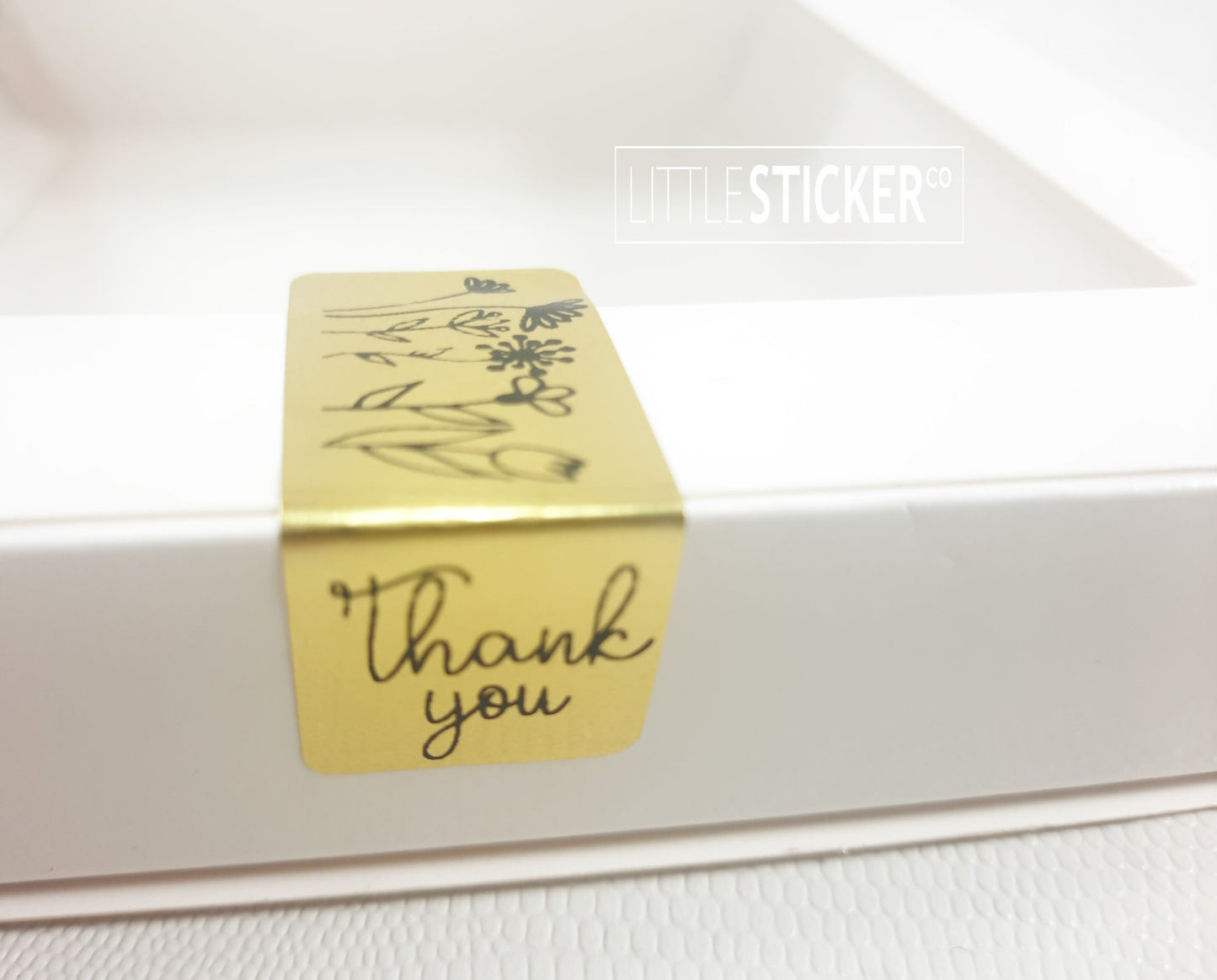 Dankeschön-Aufkleber. 50 rechteckige, goldene Aufkleber (50 x 20 mm) mit schwarzem „Danke“ und hübschen, handgezeichneten Blumen.