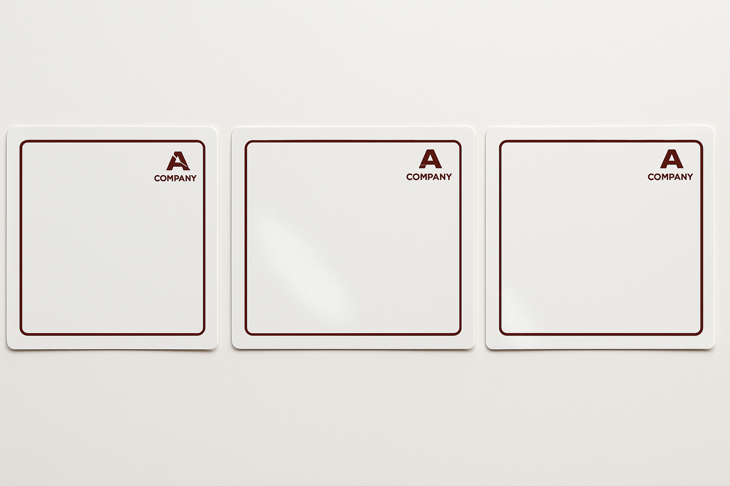 A row of glossy white stickers measuring 7cm wide and 6cm tall. The are facing in a landscape direction. Each sticker is printed with a dark red minimalist border. Each sticker has a small company logo in the top right corner in the same dark red colour