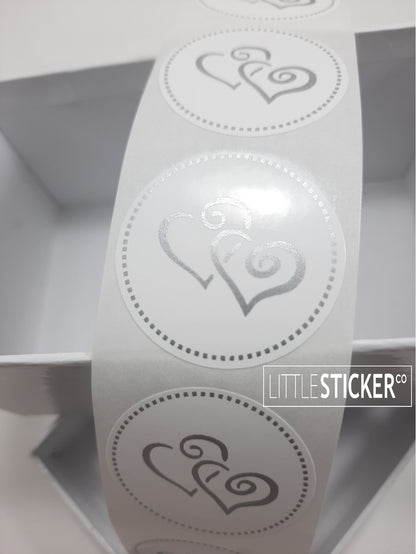 Twin heart stickers. 35mm round white stickers with matte silver twin swirly love hearts and dotted border