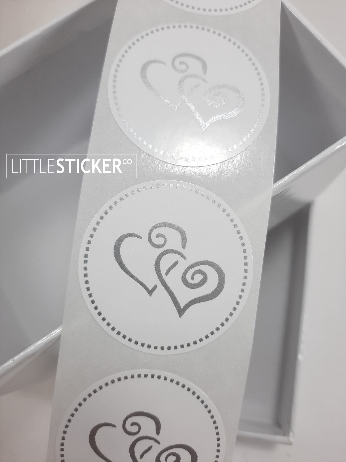 Twin heart stickers. 35mm round white stickers with matte silver twin swirly love hearts and dotted border