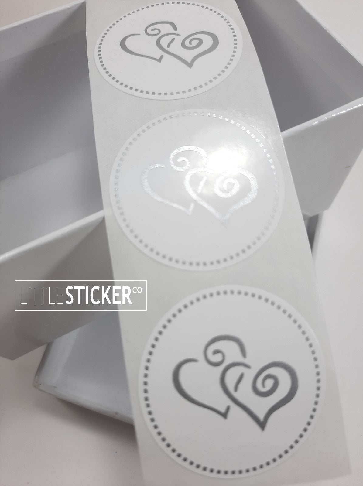 Twin heart stickers. 35mm round white stickers with matte silver twin swirly love hearts and dotted border