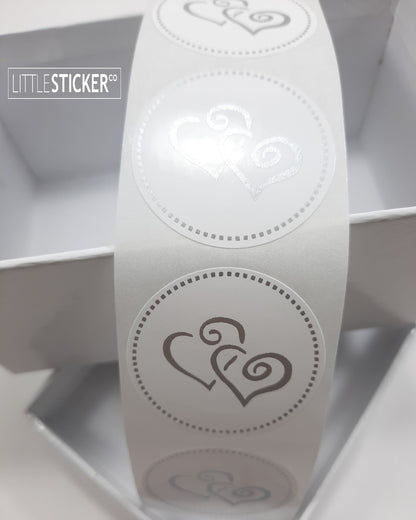 Twin heart stickers. 35mm round white stickers with matte silver twin swirly love hearts and dotted border