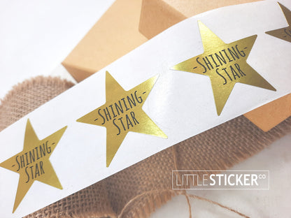 Award stickers or teacher stickers. 45mm metallic gold star shaped stickers printed with ''Shining Star''.