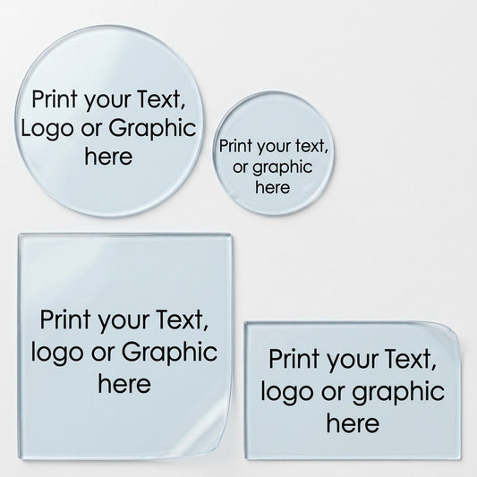 Custom printed transparent labels in three shapes: a large circle, a small circle, one square, one rectangular sticker with one having a curled bottom corner. The labels feature text reading 'Print your Text, logo or graphic here' in black on a transparent surface, set against a clean white background.