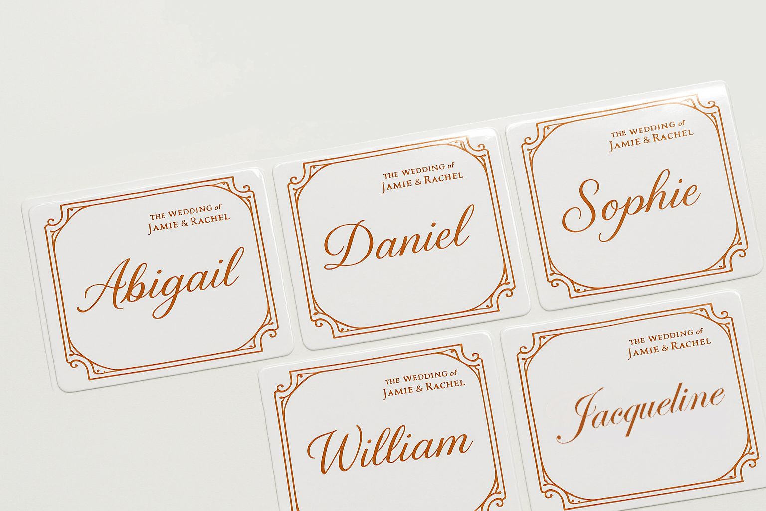 Set of personalized name stickers with orange text on a white background