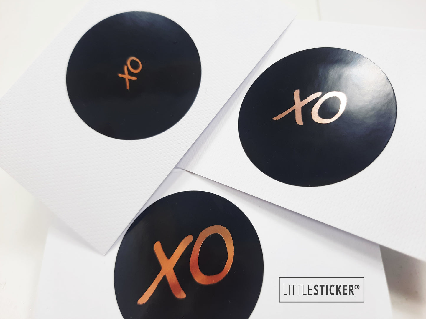 XO stickers  hand-drawn. Round gloss black stickers with rose-gold foil hugs and kisses symbol. Choice of small, medium or large print  XO