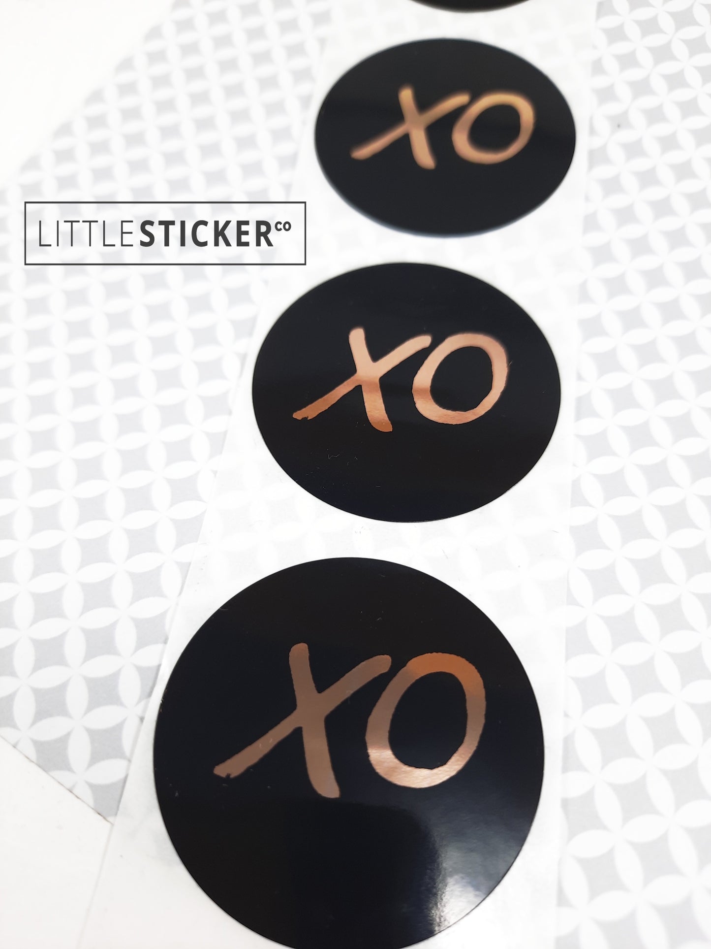 XO stickers  hand-drawn. Round gloss black stickers with rose-gold foil hugs and kisses symbol. Choice of small, medium or large print  XO