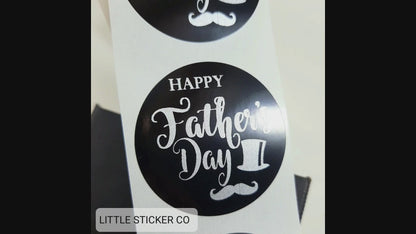 Pack of Father's Day stickers. The stickers are round and glossy black with the text ''Happy Father's Day'' printed in matte silver. The stickers also have a gentleman's top hat and moustache as a printed feature.
