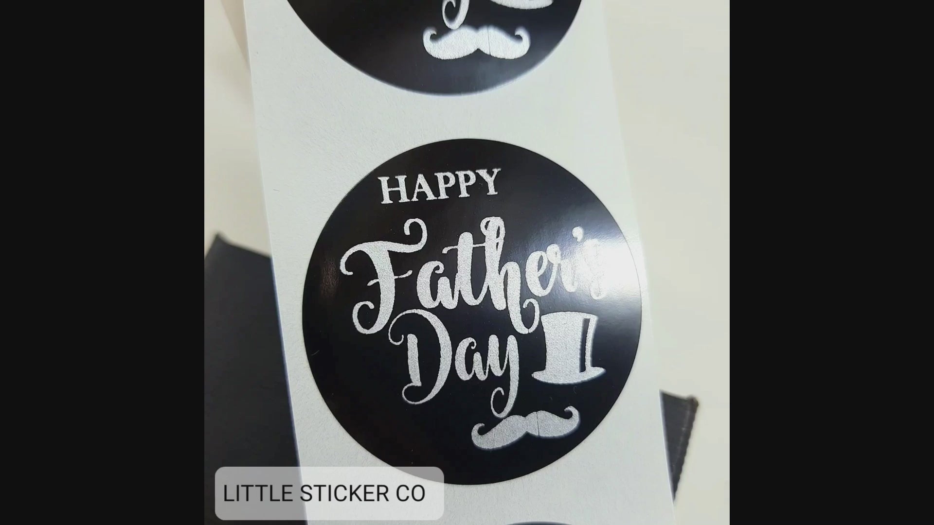 Pack of Father's Day stickers. The stickers are round and glossy black with the text ''Happy Father's Day'' printed in matte silver. The stickers also have a gentleman's top hat and moustache as a printed feature.